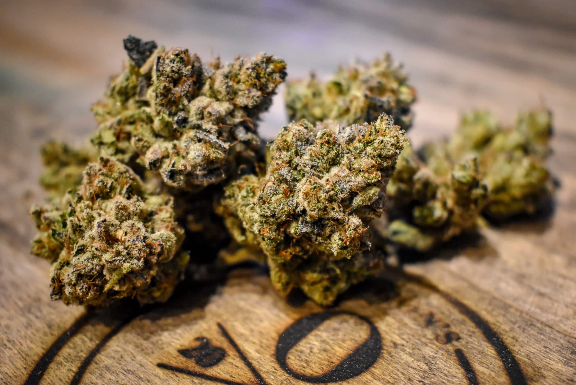 a close up of marijuana buds on a wooden board branded with the oregon's finest logo